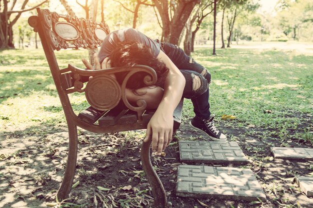 homme fatigué allongé sur un banc de bois
