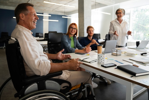 Photo gratuite homme en fauteuil roulant ayant un travail de bureau inclusif