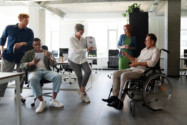 Photo gratuite homme en fauteuil roulant ayant un travail de bureau inclusif