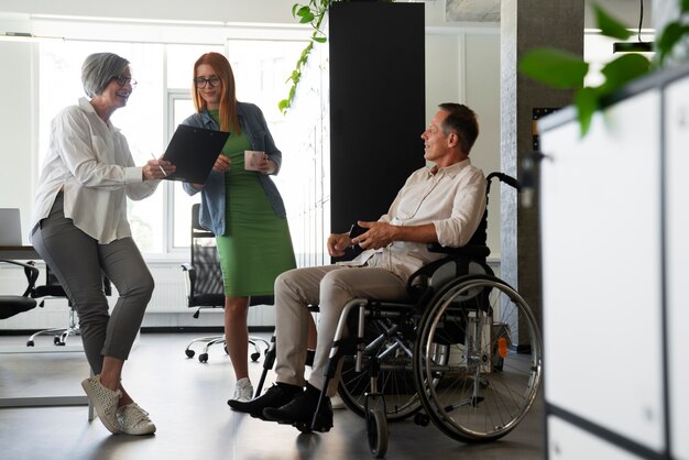 Homme en fauteuil roulant ayant un travail de bureau inclusif