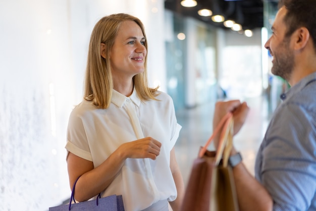 Photo gratuite homme et femme d'âge mûr en train de bavarder, de faire du shopping et de tenir des sacs en papier