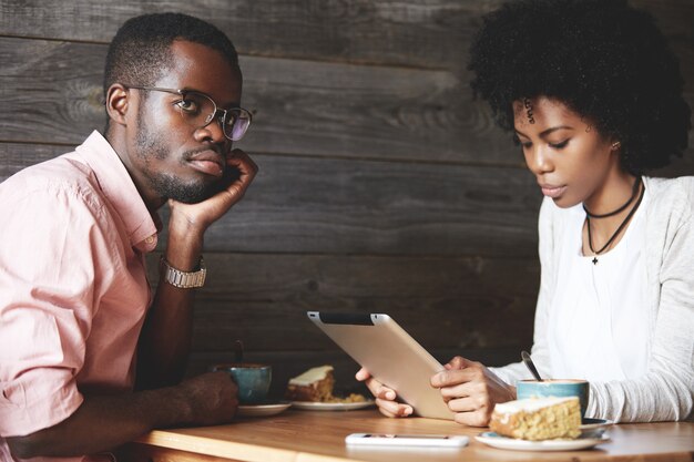 Homme et femme à l'aide de tablette au café