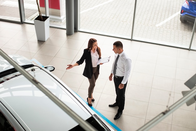 Homme et femme à angle élevé chez un concessionnaire