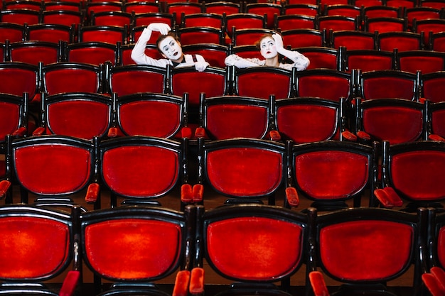 Homme et femme artiste mime assis derrière les fauteuils