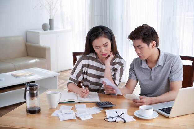 Homme et femme calculant le budget domestique à la maison