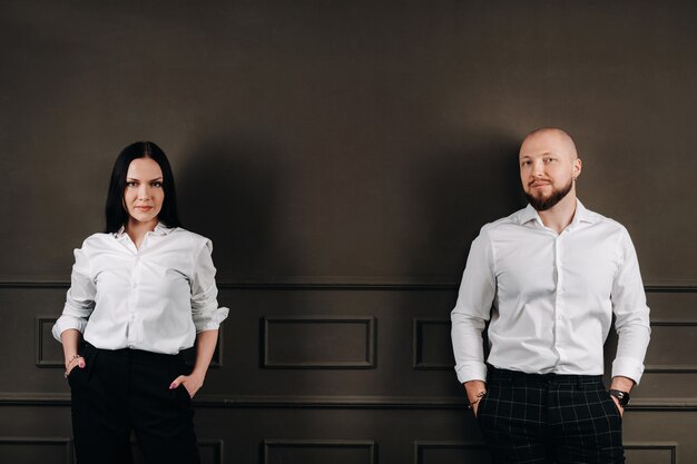 Un homme et une femme en chemises blanches sur fond noir. un couple amoureux à l'intérieur du studio.