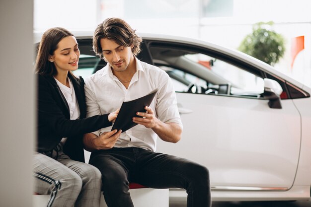 Homme et femme choisissant une voiture dans une salle d'exposition