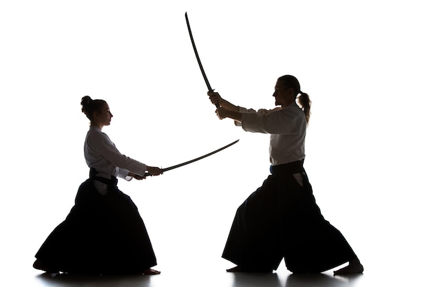 Homme et femme combattant et s'entraînant à l'aïkido sur un studio blanc
