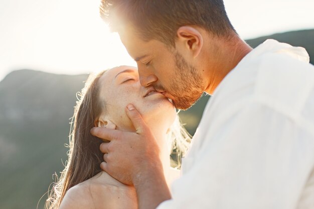 Homme et femme dans les montagnes. Jeune couple amoureux au coucher du soleil. Femme en robe bleue.