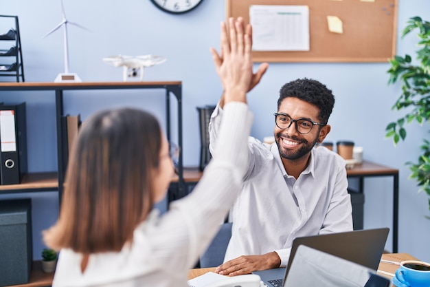 Photo gratuite homme et femme employés d'affaires high five avec les mains levées au bureau