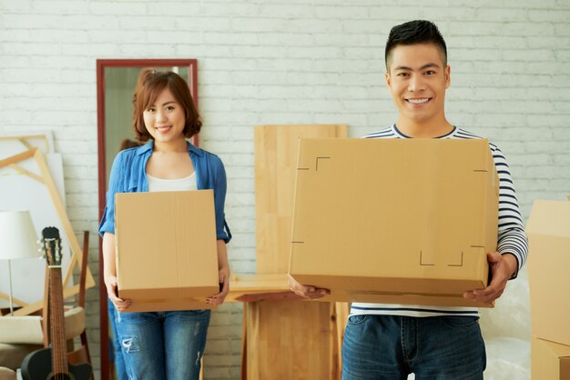 Homme et femme face à la caméra tenant des boîtes en carton