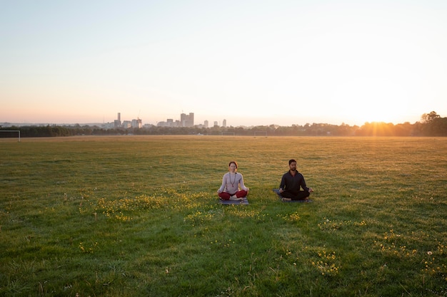 Homme et femme faisant du yoga ensemble à l'extérieur