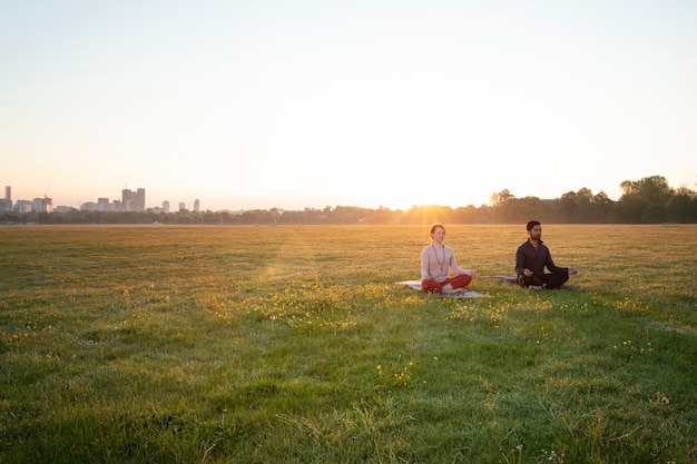 Homme et femme faisant du yoga ensemble à l'extérieur