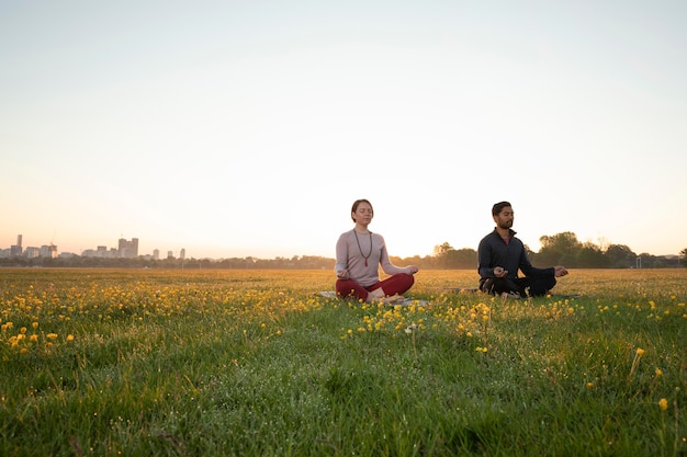 Homme et femme faisant du yoga ensemble à l'extérieur