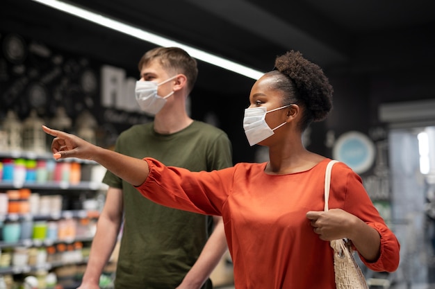 Photo gratuite homme et femme faisant leurs courses à l'épicerie tout en portant des masques médicaux