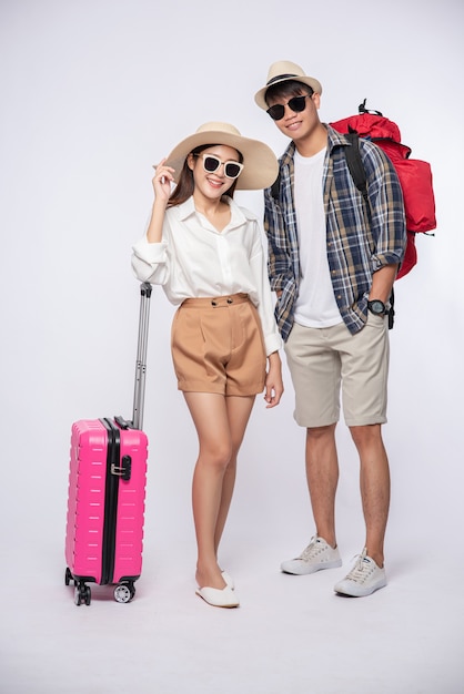Homme et femme habillés en portant des lunettes pour voyager avec des valises
