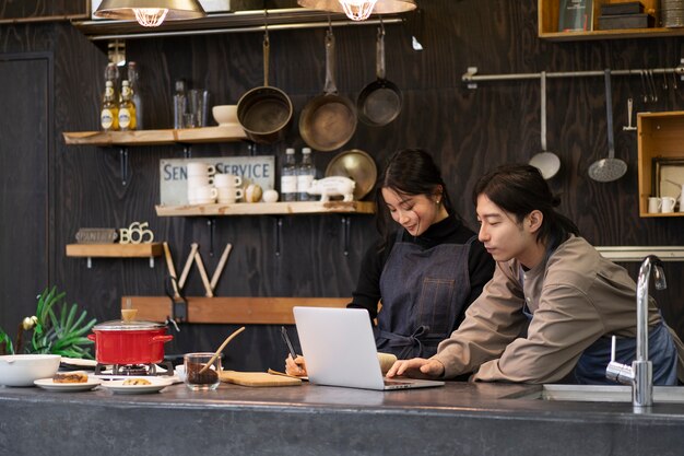 Homme et femme japonais travaillant à l'aide d'un ordinateur portable dans un restaurant