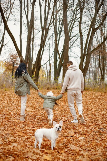 Homme femme leur petite fille et chien marchant dans la forêt d'automne