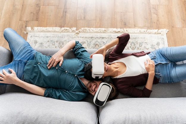 Homme et femme à la maison sur le canapé à l'aide d'un casque de réalité virtuelle