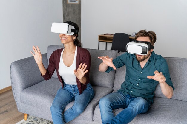 Homme et femme à la maison sur le canapé avec un casque de réalité virtuelle