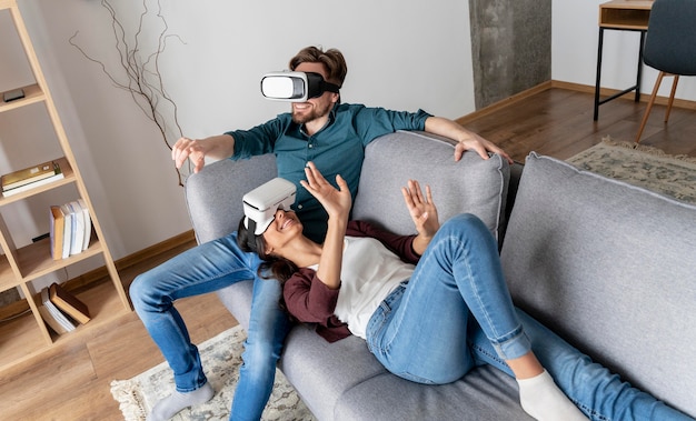 Homme et femme à la maison sur le canapé avec un casque de réalité virtuelle