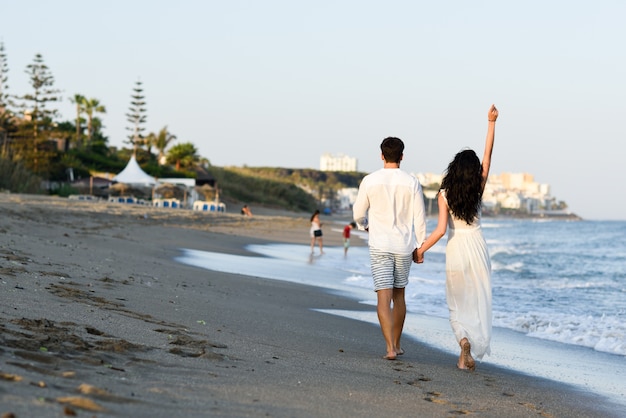 Homme et femme marchant main dans la main sur la plage