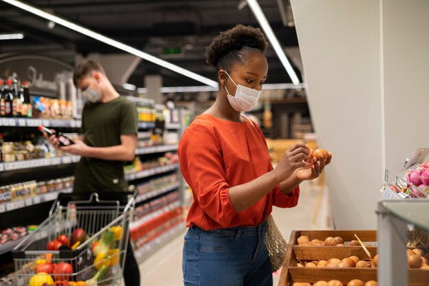 Homme et femme avec des masques médicaux à l'épicerie avec panier