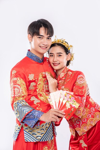 L'homme et la femme portent Cheongsam avec montrant l'argent cadeau rouge de la famille en journée traditionnelle