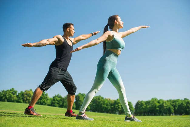 Homme et femme pratiquant le yoga en plein air