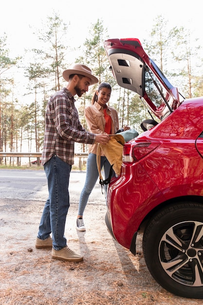 Homme et femme prenant leurs sacs à dos de leur voiture