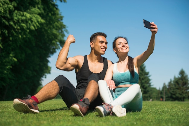 Homme et femme prenant un selfie dans un parc