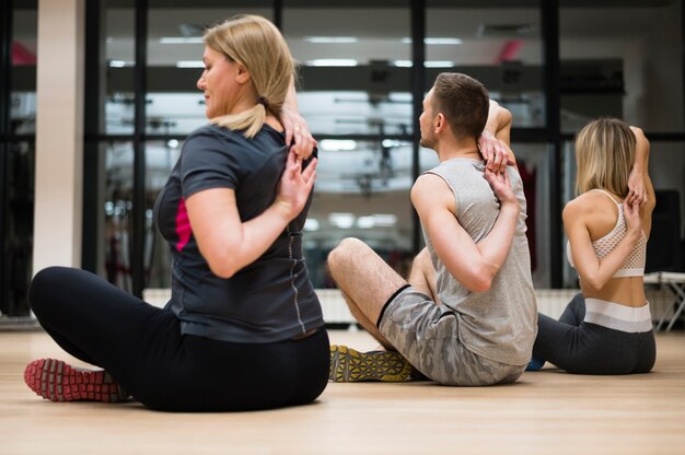 Homme et femme qui s'étirent ensemble à la gym