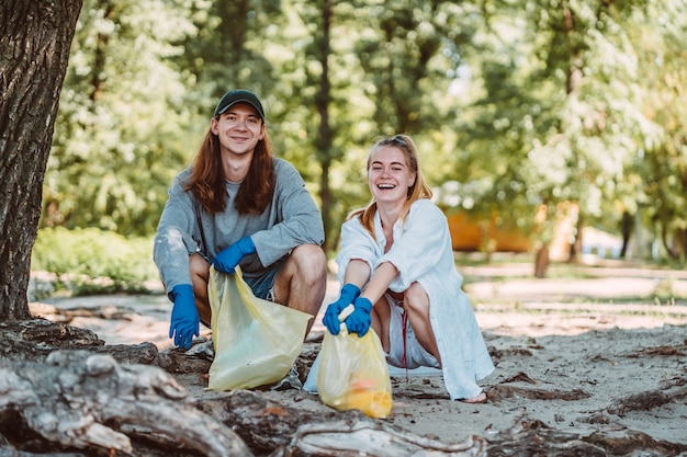 Photo gratuite homme et femme ramassant les ordures du parc. ils ramassent la litière dans un sac poubelle