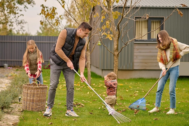 Photo gratuite homme et femme avec râteau fille près de panier dans le jardin