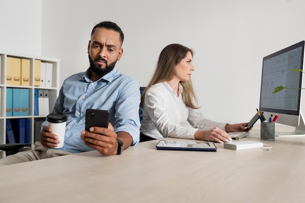 Un homme et une femme sont accros à leur téléphone même au travail