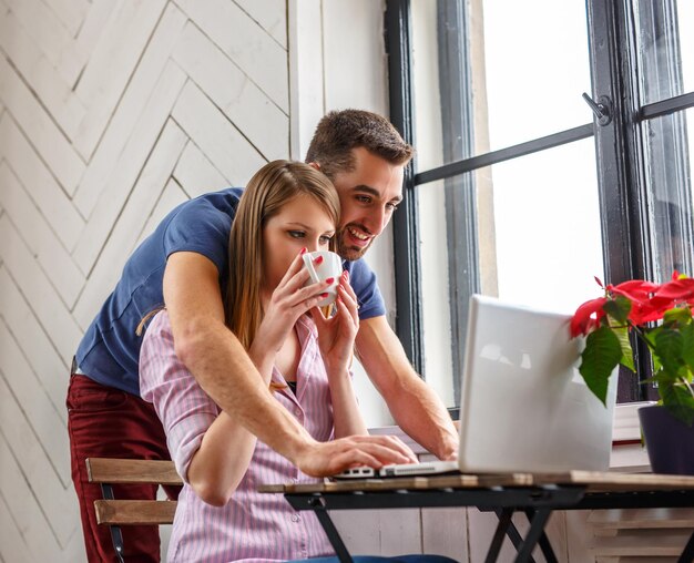 Un homme et une femme travaillant avec un ordinateur portable à la table.