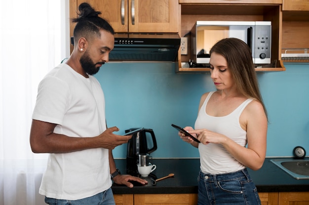 Homme et femme utilisant leur téléphone dans la cuisine