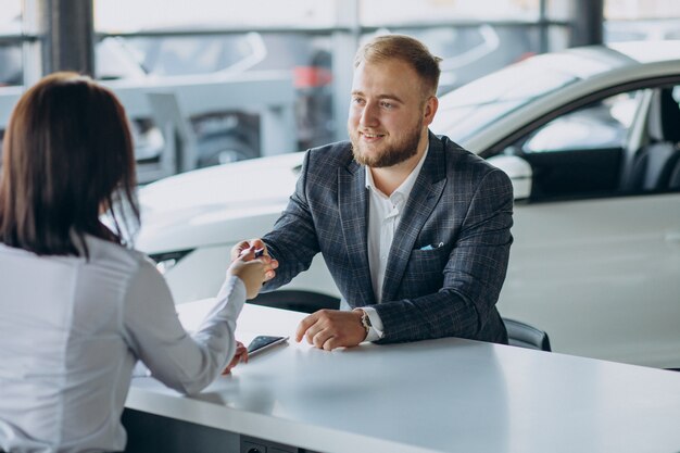 Homme avec femme de vente dans la salle d'exposition de voiture