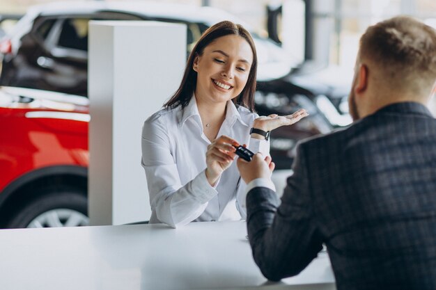 Homme avec femme de vente dans la salle d'exposition de voiture