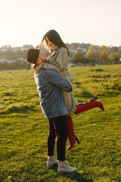 Homme et femme en vêtements de mode reposant sur une nature ensemble. Homme portant une veste et un chapeau noir et une jupe femme et des bottes rouges