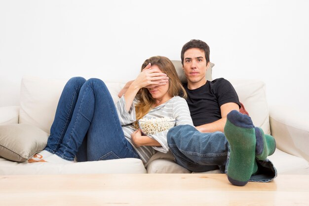 Homme fermant son œil de femme en regardant la télévision