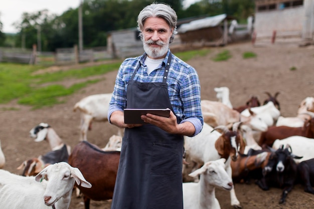 Photo gratuite homme à la ferme à la recherche sur tablette