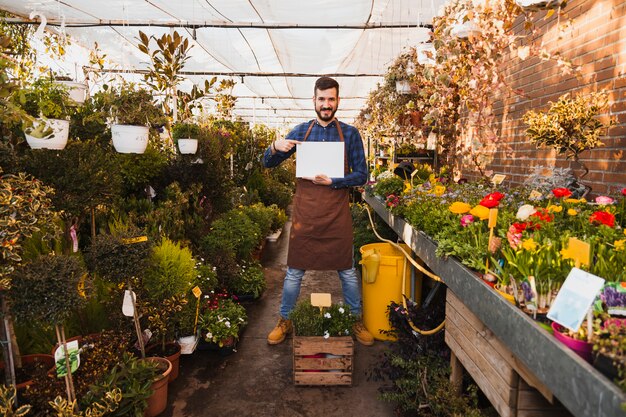 Homme avec une feuille de papier debout dans la serre