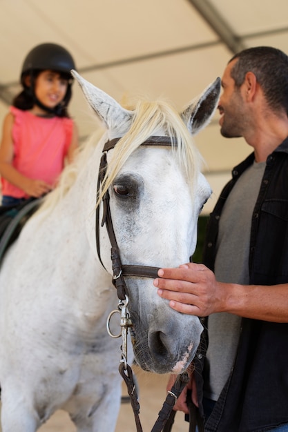 Photo gratuite un homme et une fille avec un cheval.