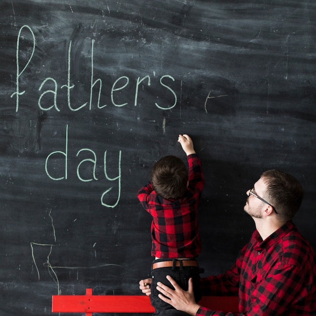 Homme avec fils écrit sur le tableau le jour des pères