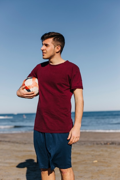 Homme avec le football à la plage