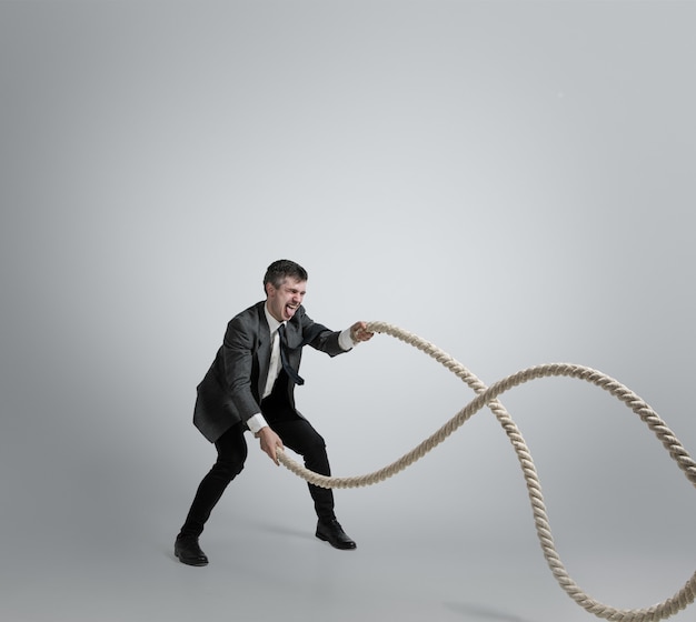 Homme en formation de vêtements de bureau avec des cordes sur fond gris.