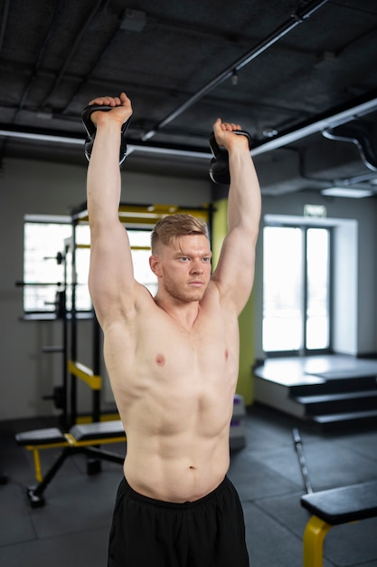 Homme en forme de coup moyen s'entraînant avec des kettlebells