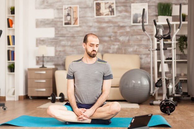 Homme en forme regardant un cours de yoga en ligne pendant le verrouillage de covid-19.