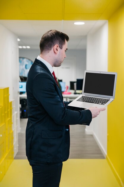 Homme formel au bureau montrant un ordinateur portable